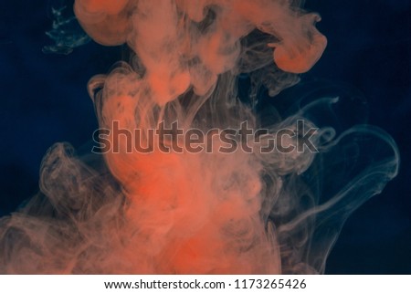 orange paint on a dark blue background like a cloud of steam dissolves in the water fantastic abstraction