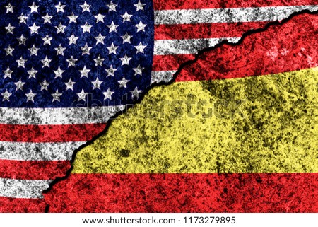 two flags of the USA and Spain on a cracked concrete wall
