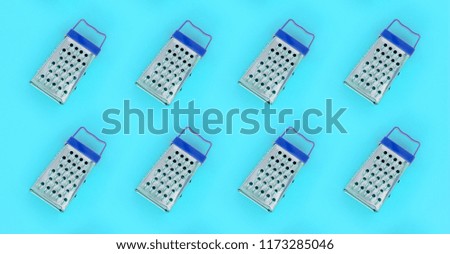 Small stainless steel graters lies on a pastel colored paper. Kitchen accessories. Tools for cooking. Flat lay top view.