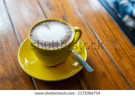 A cup of coffee latte on the wood table with latte art.
