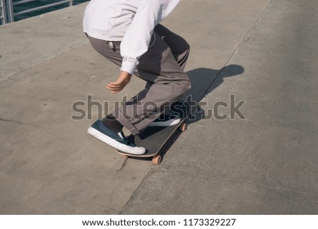 Young male skates low on a pier