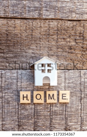 Miniature toy model house with inscription HOME letters word on wooden backdrop. Eco Village, abstract environmental background. Real estate mortgage property insurance sweet home ecology concept