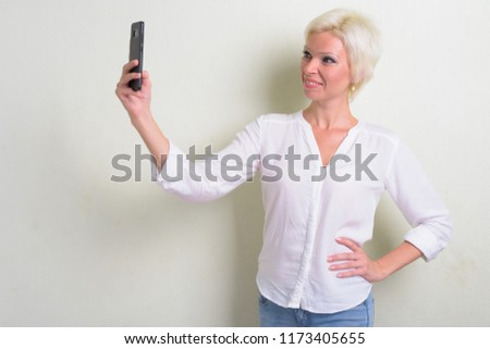 Happy blonde businesswoman with short hair taking selfie
