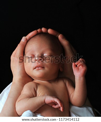 baby in mother's arms and wrapped up in white blanket just been cared for after having a good sleep in bed stock photograph stock photo Royalty-Free Stock Photo #1173414112