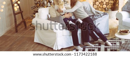 the family near the fireplace and the Christmas tree sits on the couch, the girl reaches out to her father, hug him. Congratulations,Christmas morning