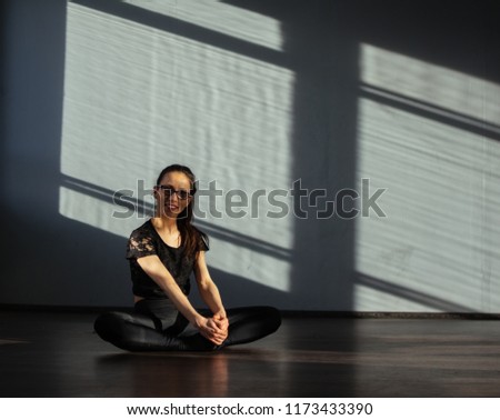 A girl in the dance hall sits on the floor and warms up before training