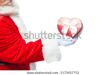 Christmas. Santa Claus in white gloves holds a red heart shaped gift box with a white ribbon. Isolated on white background. Close up