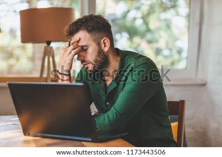 Young man having stressful time working on laptop Royalty-Free Stock Photo #1173443506