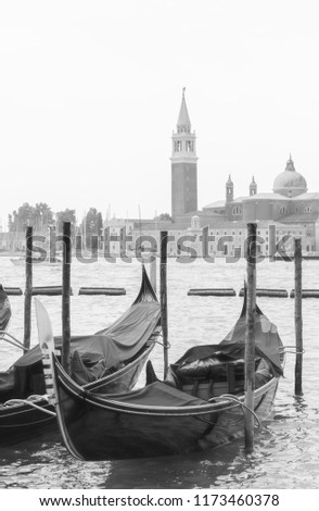 two gondolas moored to the poles in the foreground and the church of San Giorgio Maggiore in the background, black and white photography with a winter atmosphere