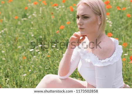 beautiful blonde hair girl sitting in the poppy field - summer portrait