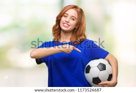 Young beautiful woman over isolated background holding soccer football ball very happy pointing with hand and finger