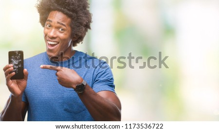Afro american man holding broken smartphone over isolated background very happy pointing with hand and finger