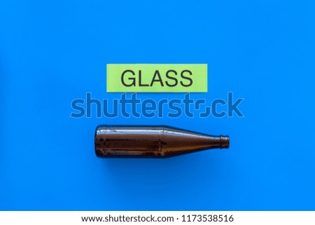 Waste suitable for recycle. Glass bottle near printed word glass on blue background top view copy space