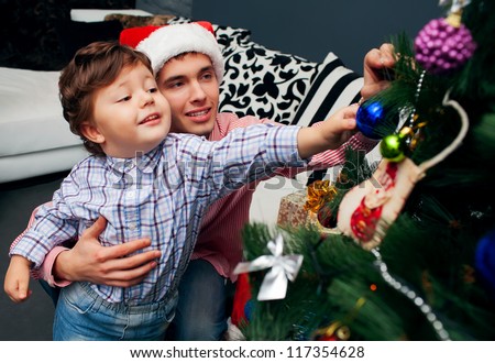 Smiling father and his son opening Christmas presents in the living-room
