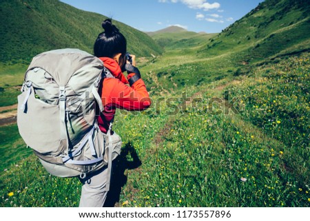 Woman hiker taking photo in the  high altitude grassland mountains