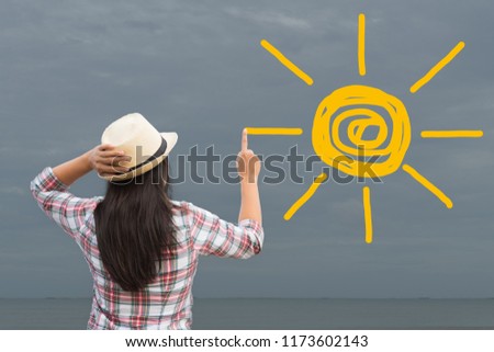 Woman drawing or painting sun onto grey sky. need sun light. change concept.