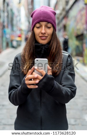 Young woman smiling and taking a selfie with her smartphone