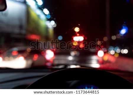 image of people driving car night time with raindrop on glass  for background usage.(take photo from inside)