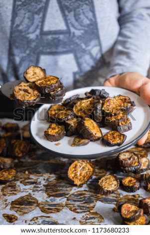 Woman hands holds roasted, grilled eggplants round slices with oregano herbs, spices baked on parchment paper in oven. Vegan vegetarian healthy lunch or dietary dinner.