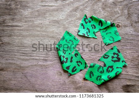 Recycling logo from green fabric over wooden background