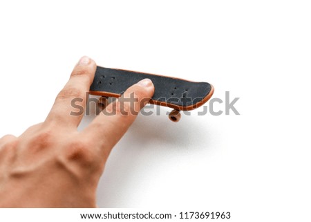 Fingerboard. A small skateboard and a hand. Close up. Isolated on white background