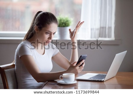 Mad young female annoyed with scam or spam messages on smartphone, frustrated woman receive bad news on cell, confused girl get phone problems having no signal, bothered with not working device Royalty-Free Stock Photo #1173699844