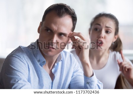 Annoyed husband tired of wife scolding or lecturing him, millennial couple having fight or disagreement at home, bothering woman press exhausted and nervous man. Breakup or separation concept Royalty-Free Stock Photo #1173702436
