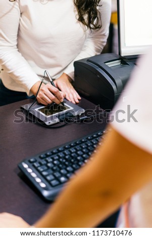 Woman using a Payment terminal, digital electronic signature in a shop