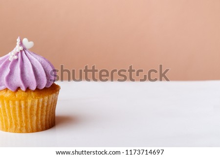 cute cupcake with small white heart on purple cream on pink background