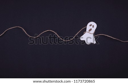 Decoration for Halloween party - laughing flying scary specter or spirit, handing on a rope on a black background. Flat lay