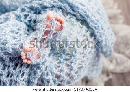 Newborn baby feet on knitted plaid. Closeup picture