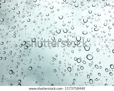 Rain drops on window glasses surface with cloudy background.Natural Pattern of raindrops isolated on cloudy background.