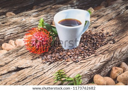 Coffee mug with coffee beans on wooden slab and flower