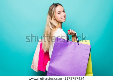 Portrait of excited beautiful girl holding shopping bags isolated over blue background