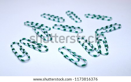 Green office paper clips on a white background