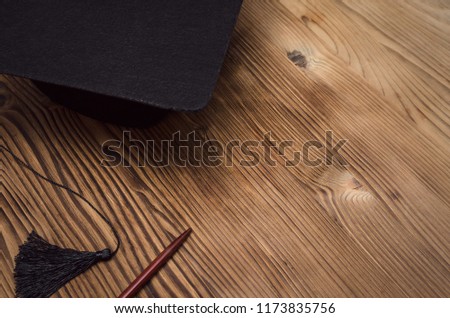 Graduate cap and school pointer on the wooden school desk with copy space.