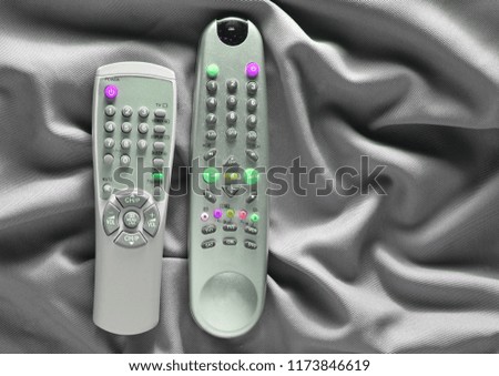 TV remote controls on a gray silk background
