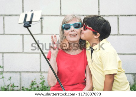 funny Grandmother and Grandson with sunglasses taking selfie using smartphone