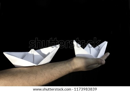 holding paper boats with his hand