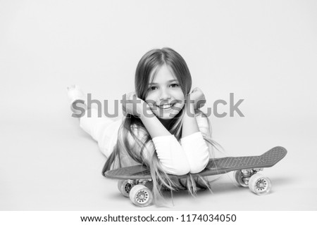 Small girl smile with skate board on pink background. Child skater smiling with longboard. Skateboard kid lie on floor. Childhood lifestyle and active games. Sport activity and energy, punchy pastel.