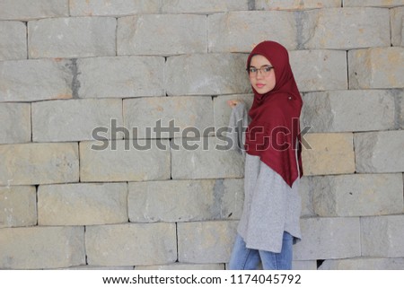 Portraiture of cute girl wearing hijab and casual outfit at park with greenery background.