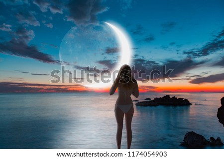 Beautiful young woman resting on beach in summer with super moon at dusk "Elements of this image furnished by NASA "