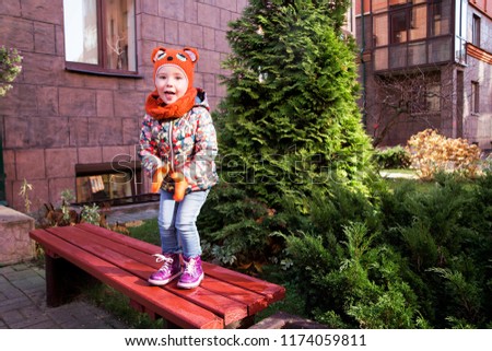 photo of little girl jumping on the bench under the entrance