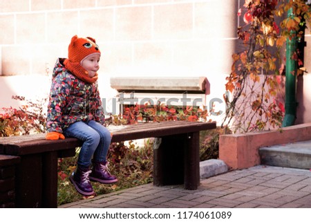 photo of little girl sitting alone on the bench