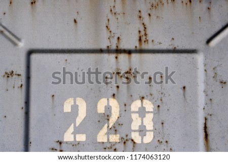 Numbers 228 painted on old rusty metal wall with copy space for design. Two hundred twenty-eight
