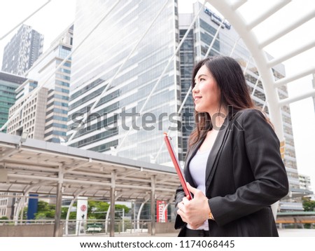 the asian business woman hold the contract on the clip board in the city, looking forword with confident.