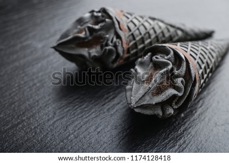 Black ice cream in cone on black slate background closeup