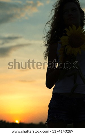 Silhouette of a girl with curly hair on background of the sun. Sunset or sunrise