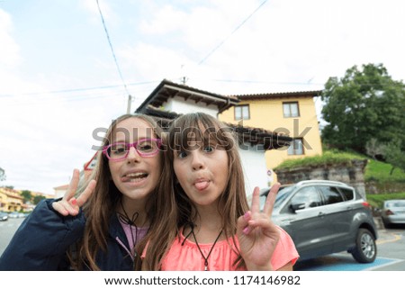 portrait of two girls joking while their fingers make the sign of victory