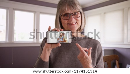 Charming old female showing video of pregnant daughter with husband on phone
